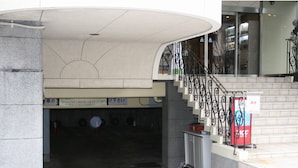 A parking garage entrance with a curved ceiling, a staircase with ornate metal railings, and a sign with Japanese text. - Fukui Palace INN (Fukui)