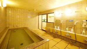 Casa de banho com uma banheira grande, zona de duche e um espelho com produtos de higiene pessoal.