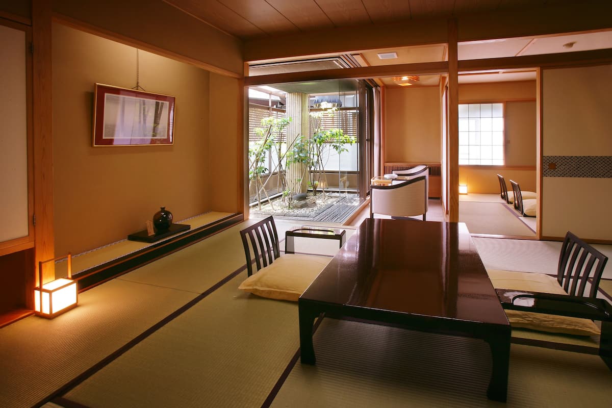 A traditional Japanese room with tatami flooring, a low table, and a sliding door leading to a garden.