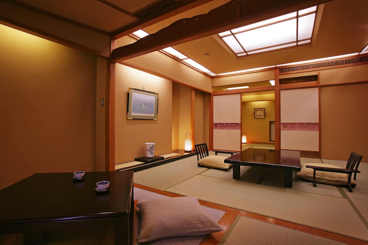 A traditional Japanese room with tatami flooring, a low table, cushions, and a sliding door.