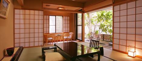 Una habitación japonesa tradicional con suelo de tatami, una mesa baja y puertas correderas.
