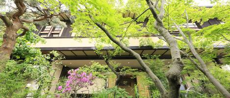 A traditional building with a covered entrance, surrounded by lush greenery and trees.