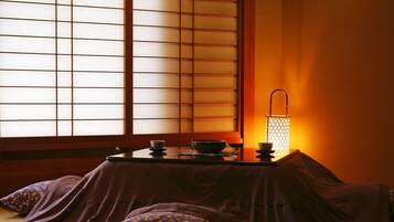 A traditional Japanese room with tatami flooring, a low table, and a lantern providing warm light.
