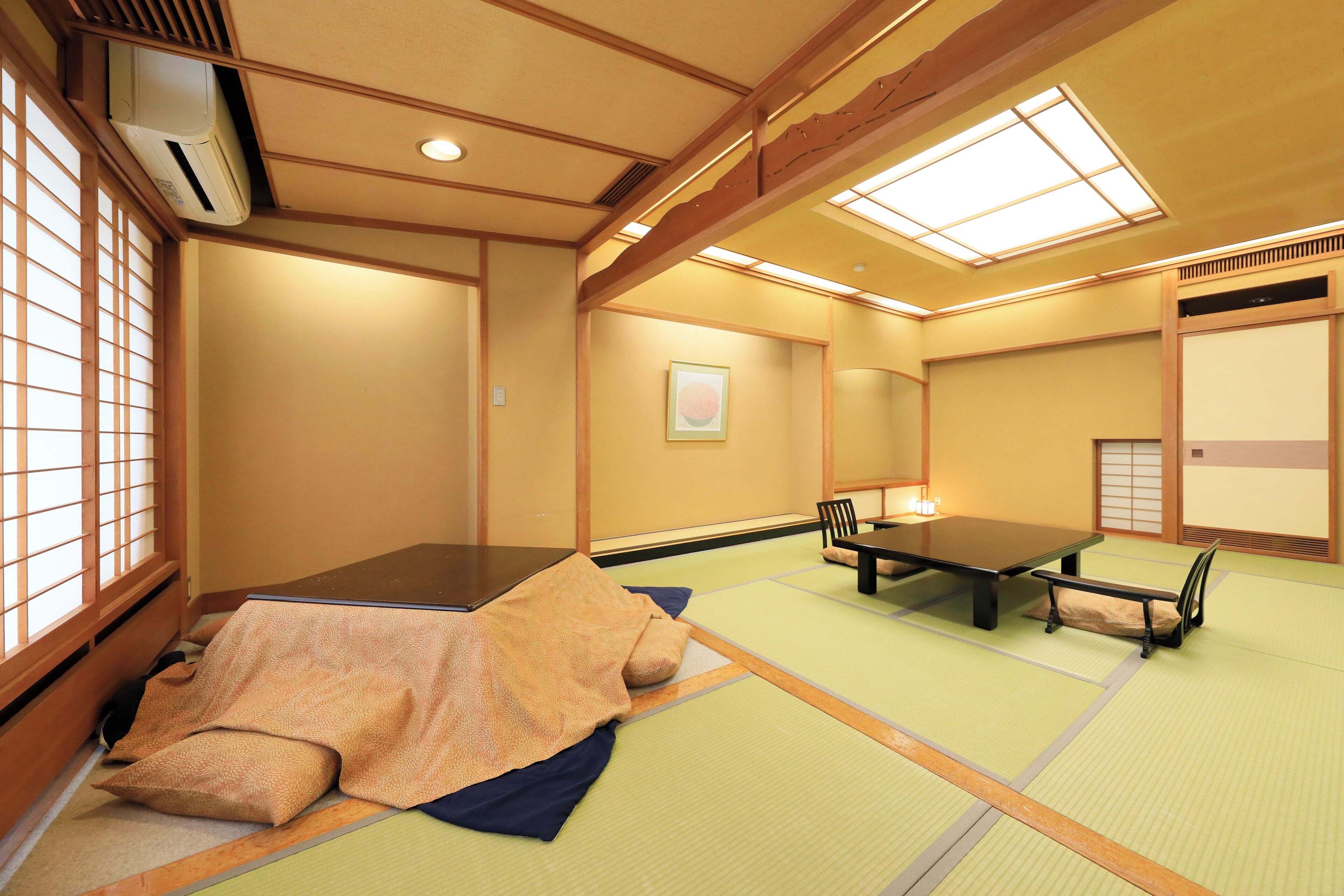 A traditional Japanese tatami room with a low table and seating, a sliding door, and a window with shoji screens.