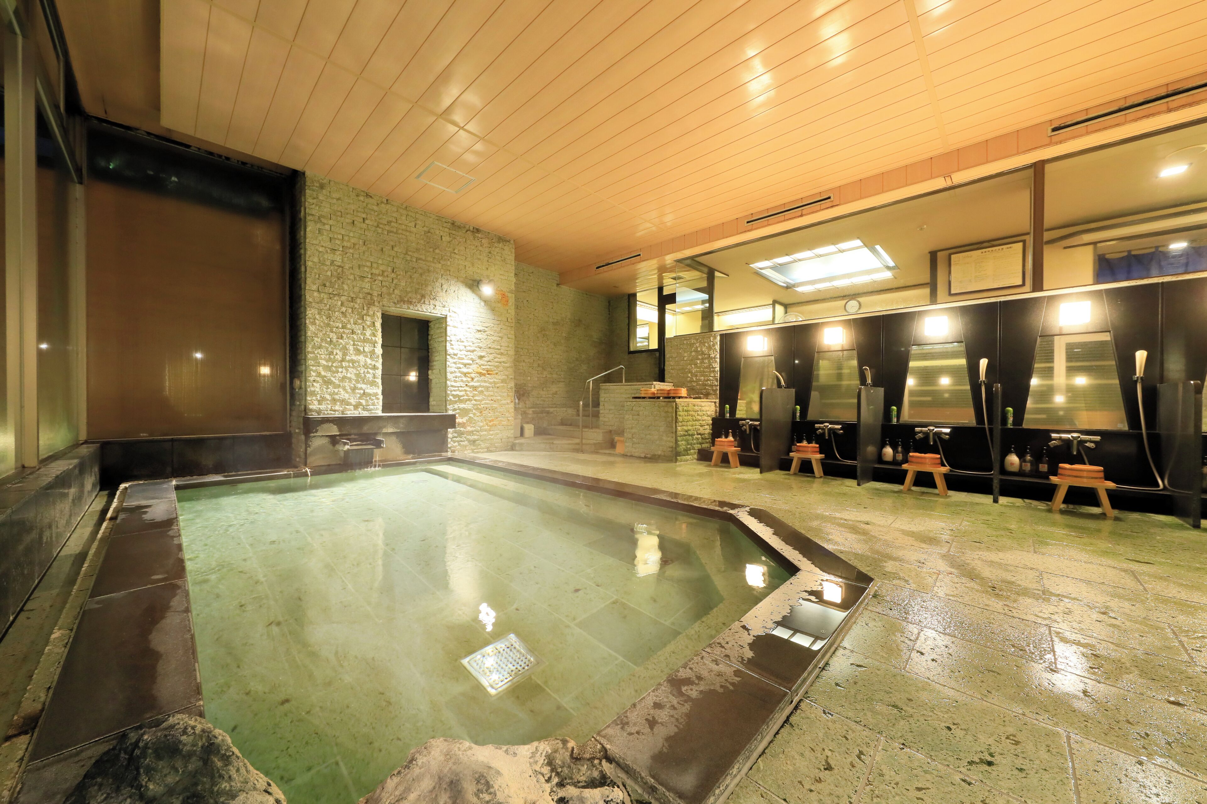 A spa area with a hot tub, stone walls, wooden ceiling, and a row of changing rooms.