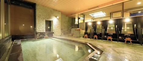 A spa area with a hot tub, stone walls, wooden ceiling, and a row of changing rooms.