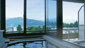 Una habitación con un ventanal grande que ofrece vistas a un paisaje urbano y montañas.