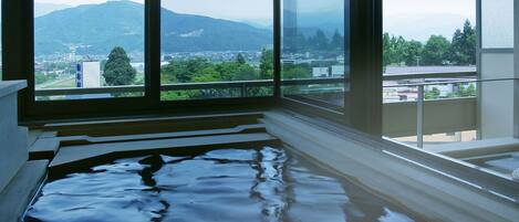 A room with a large window overlooking a cityscape and mountains.