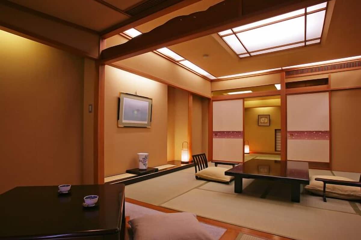 A traditional Japanese-style room with tatami flooring, a low table, and a cushioned chair.