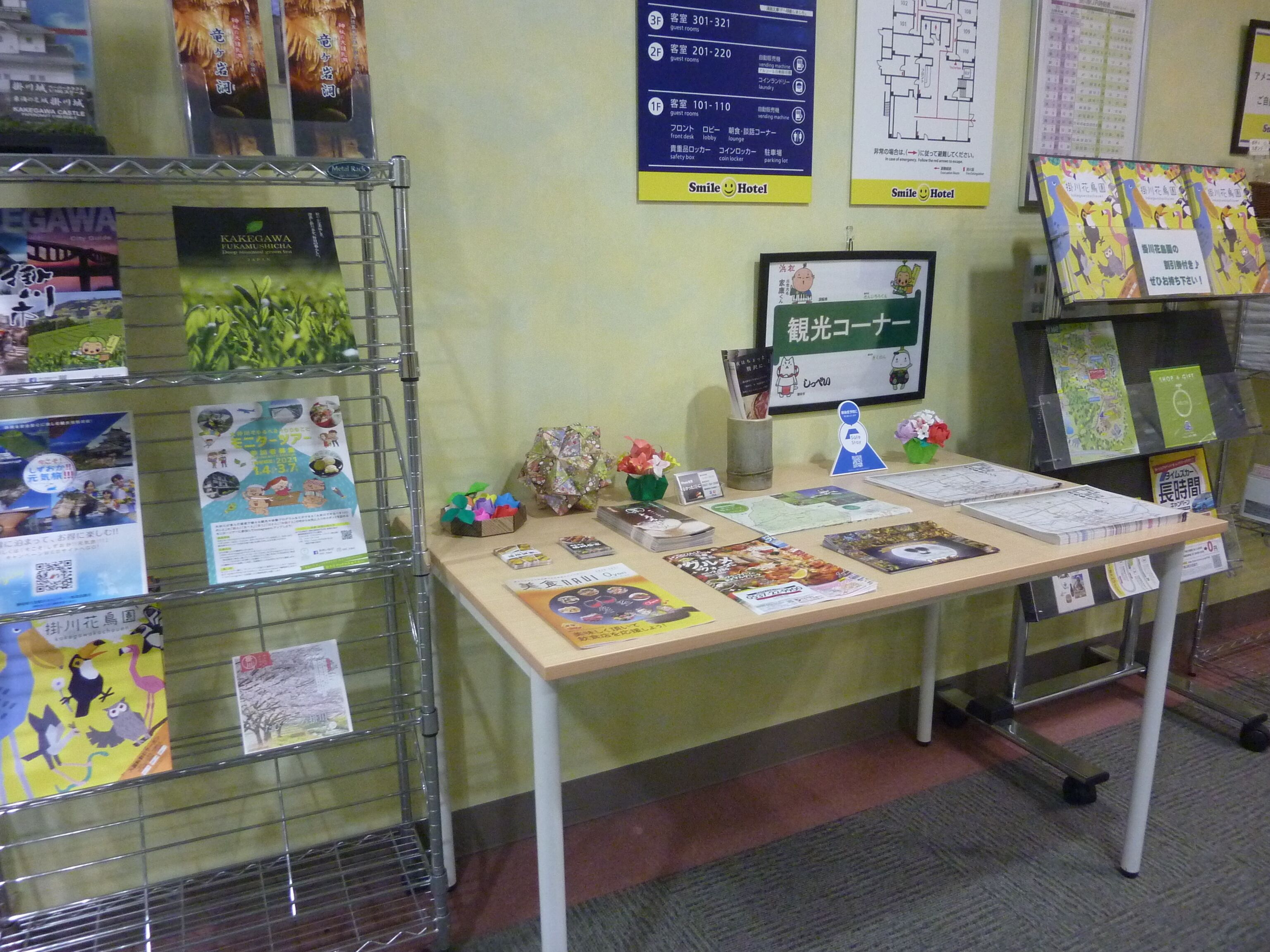A hotel reception desk with informational posters, a map, and a variety of brochures.