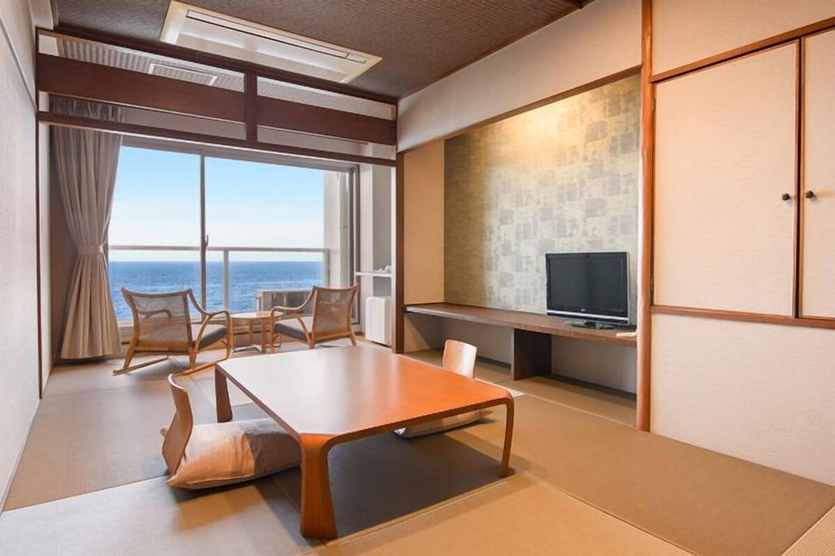 A room with a balcony, a television, and a dining area.