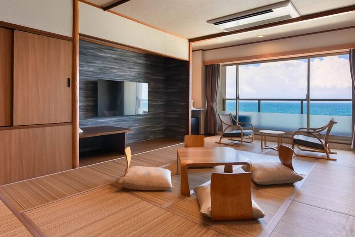 A modern room with a large window, a flat-screen TV, and a seating area with chairs and a table.