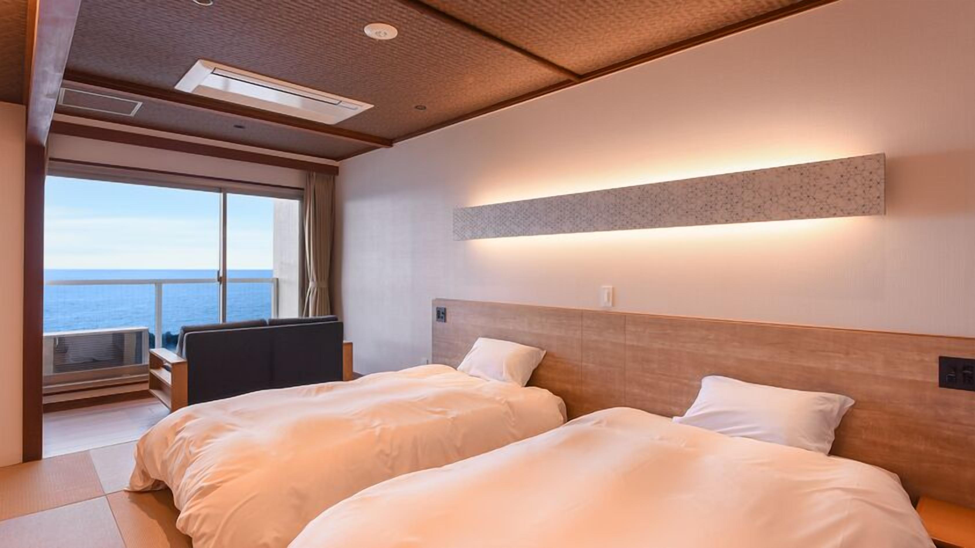 Ett hotellrum med två sängar, ett skrivbord och ett stort fönster med utsikt över havet.