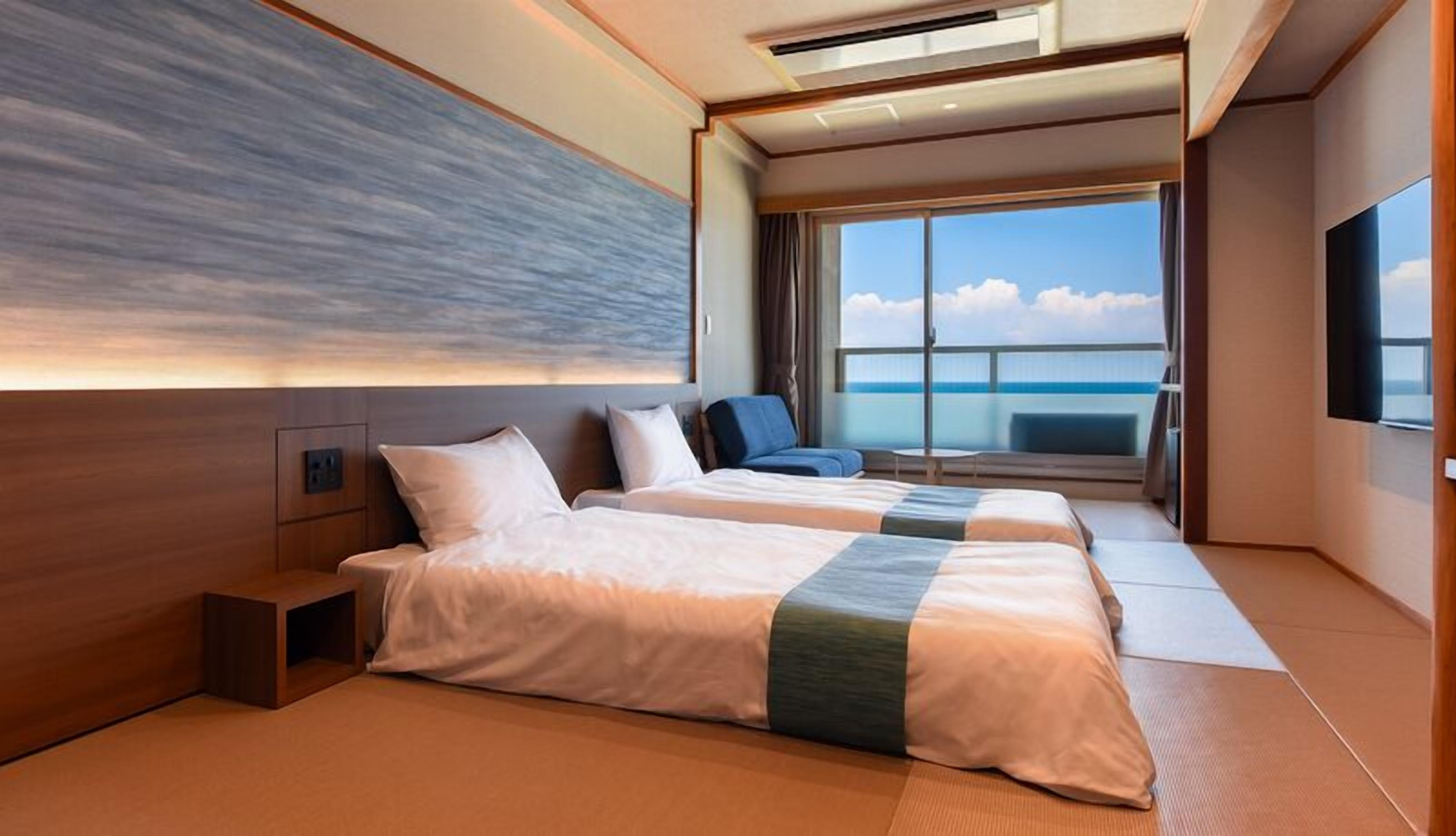 Ett modernt hotellrum med två sängar, ett stort fönster med utsikt över havet och en platt-TV.