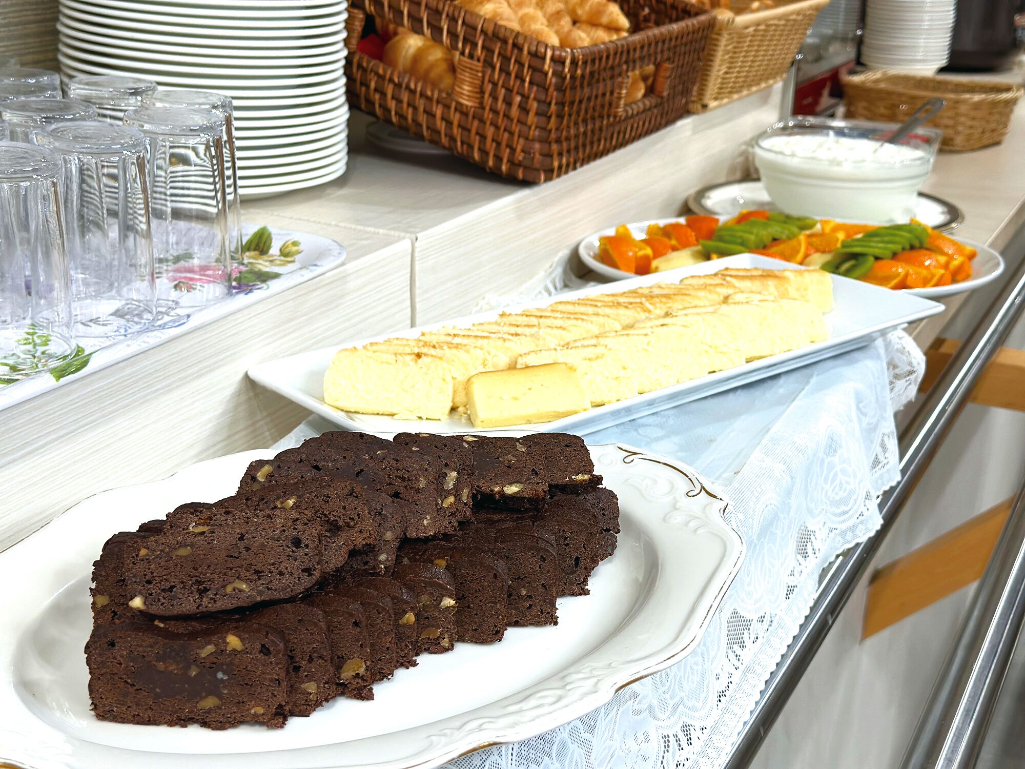 Una mesa de bufé con fuentes de brownies, un pastel y diversas frutas.