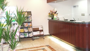 Un área de recepción con un mostrador de madera, una estantería y un arreglo floral.