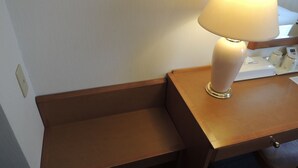 Una mesita de noche de madera con una lámpara y una pequeña bandeja.