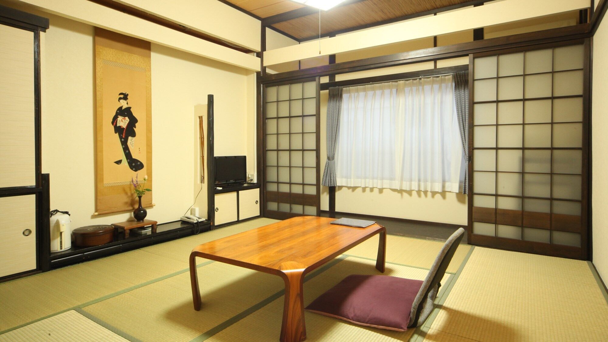 A traditional Japanese room with tatami flooring, a low wooden table, a futon, a shoji screen, and a sliding door.