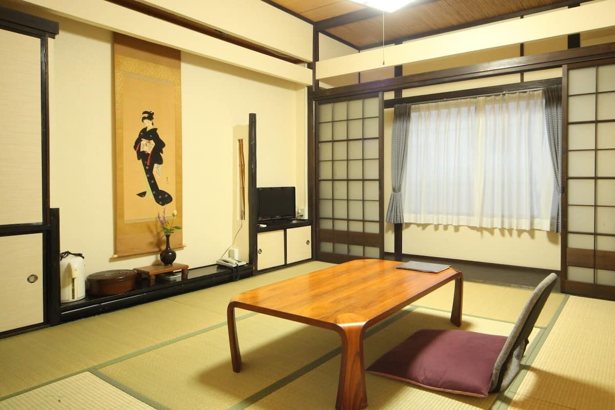 Perinteinen japanilainen huone, jossa on tatamimatto, matala puupöytä, futon-patja, shoji-paperi-seinä ja liukuovi.