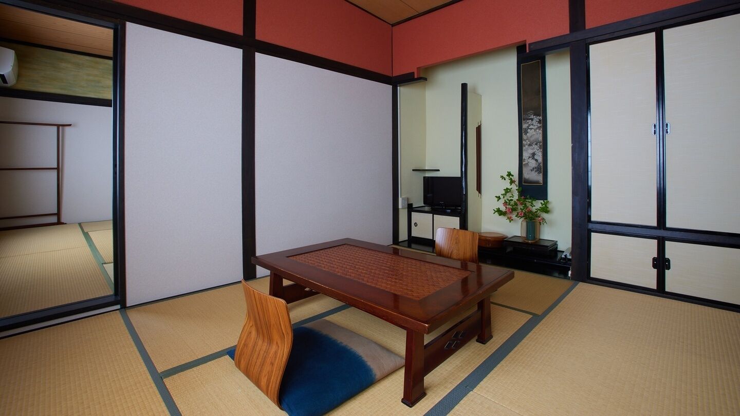 A traditional Japanese room with tatami flooring, a wooden table, and sliding doors.