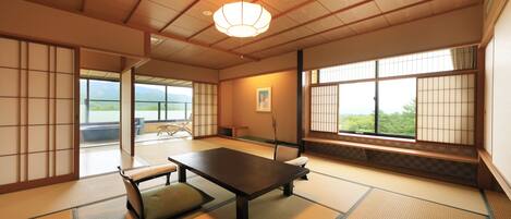 Una habitación japonesa tradicional con suelo de tatami, una mesa baja y puertas correderas.