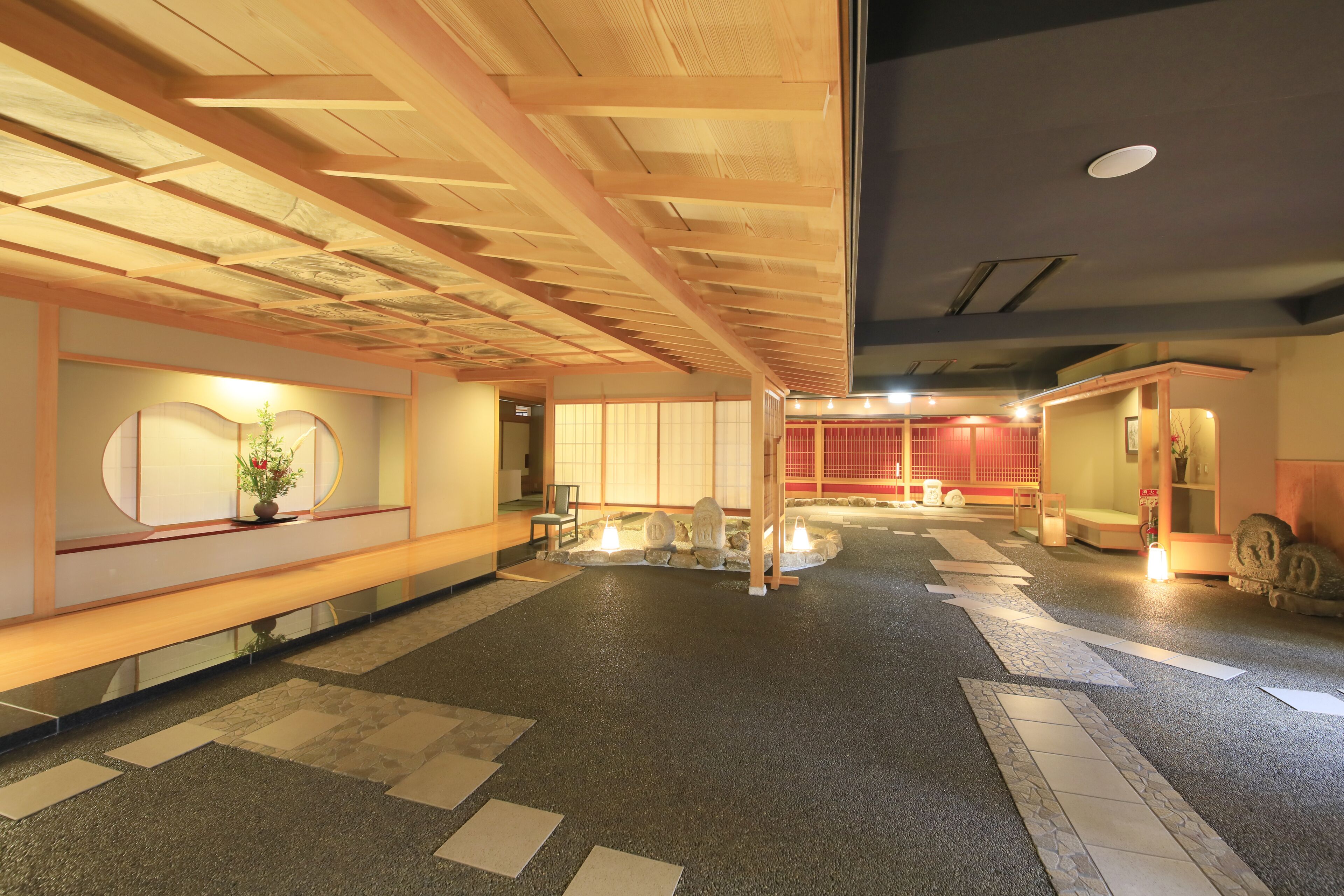 A spacious lobby with a wooden ceiling, a reception desk, and a traditional Japanese interior.