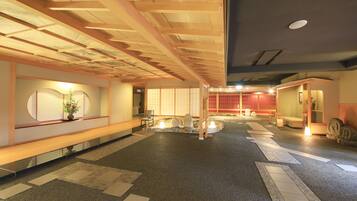 Eine großzügige Lobby mit Holzbalkendecke, einer Rezeption und einer traditionellen japanischen Innenausstattung.