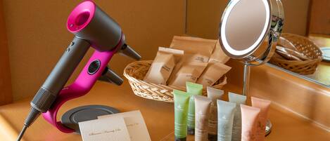 Un secador de pelo, un espejo y varios productos para el cuidado del cabello sobre una superficie de madera.