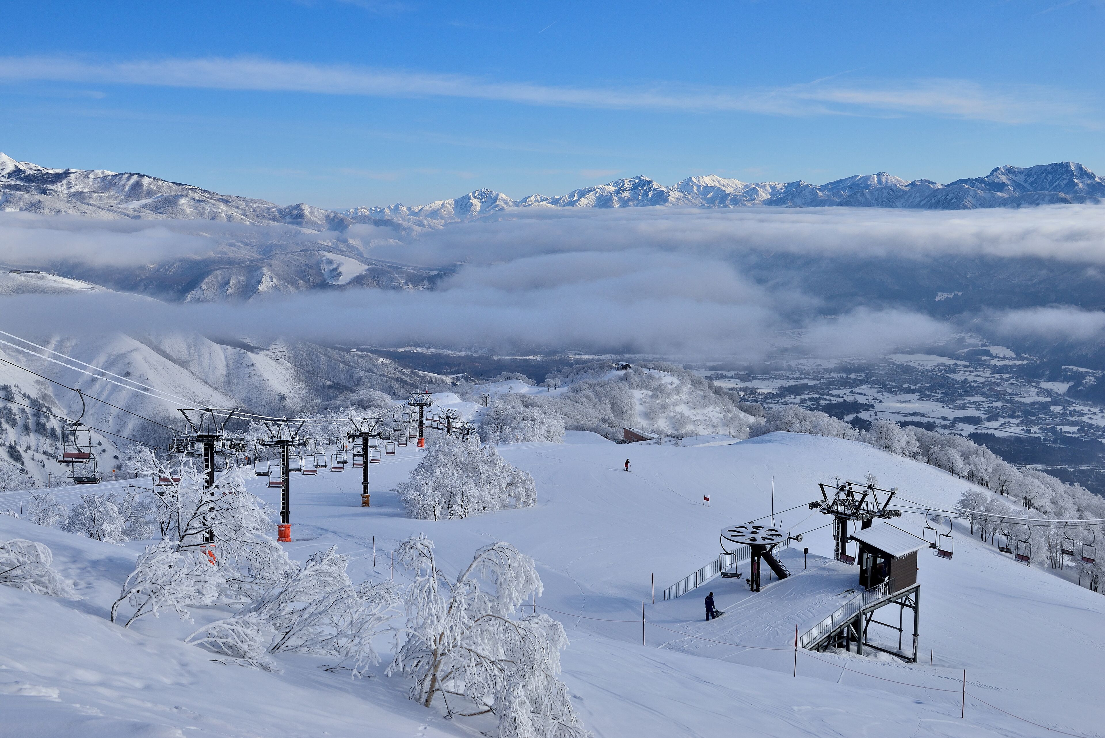 Estância de esqui coberta de neve, com teleféricos e gôndolas, e vista para a montanha.