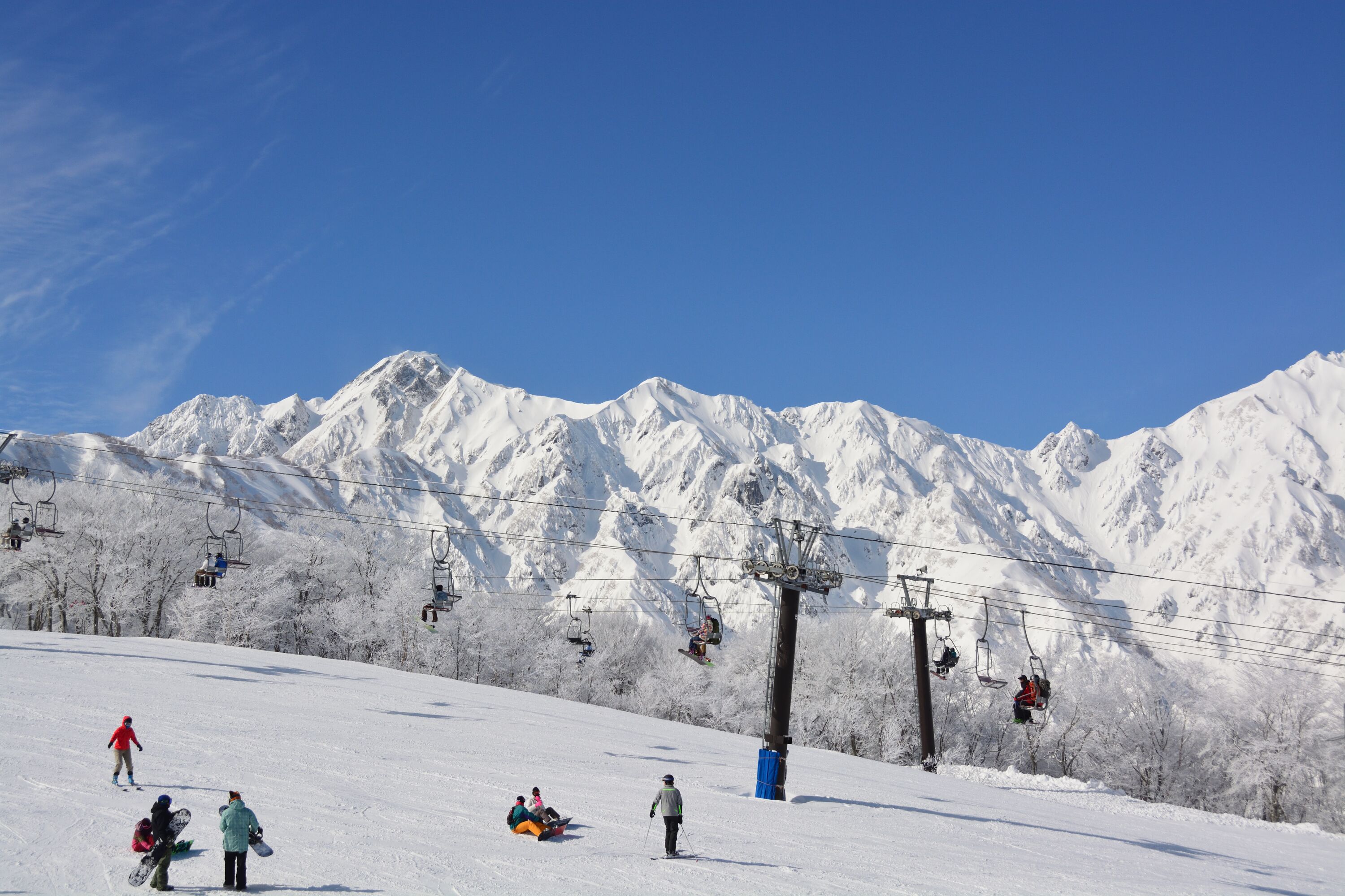 A snowy mountain slope with ski lifts and skiers.