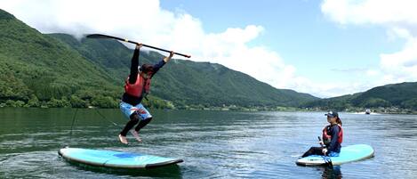 Two people on paddleboards in a calm lake with mountains in the background.