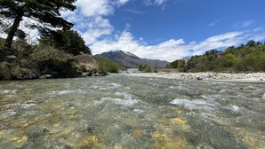 A river with clear water, surrounded by trees and mountains in the background. - Hotel Keisui (Omachi)