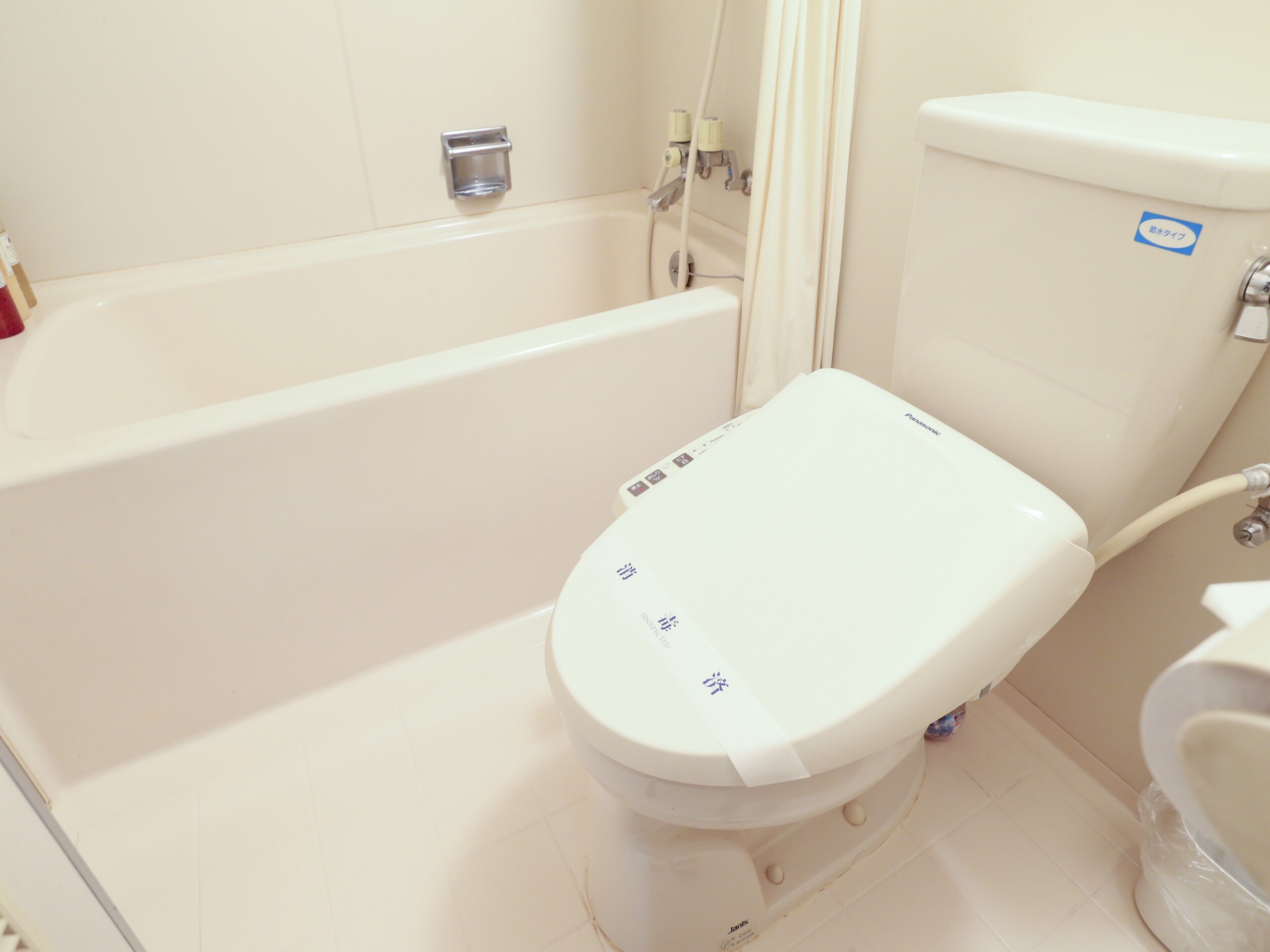 Un baño con inodoro blanco, bañera y zona de ducha.