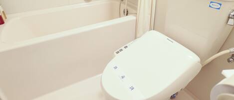 Un baño con inodoro blanco, bañera y zona de ducha.