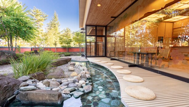 A modern building with a glass facade, a landscaped garden with a water feature, and outdoor seating. - Hotel Keisui (Omachi)