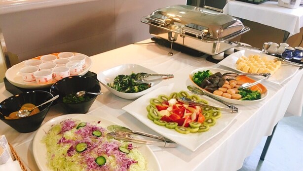 A buffet table with various dishes including salads, fruits, and a covered dish. - Business Hotel Sunshine Takamatsu (Takamatsu)