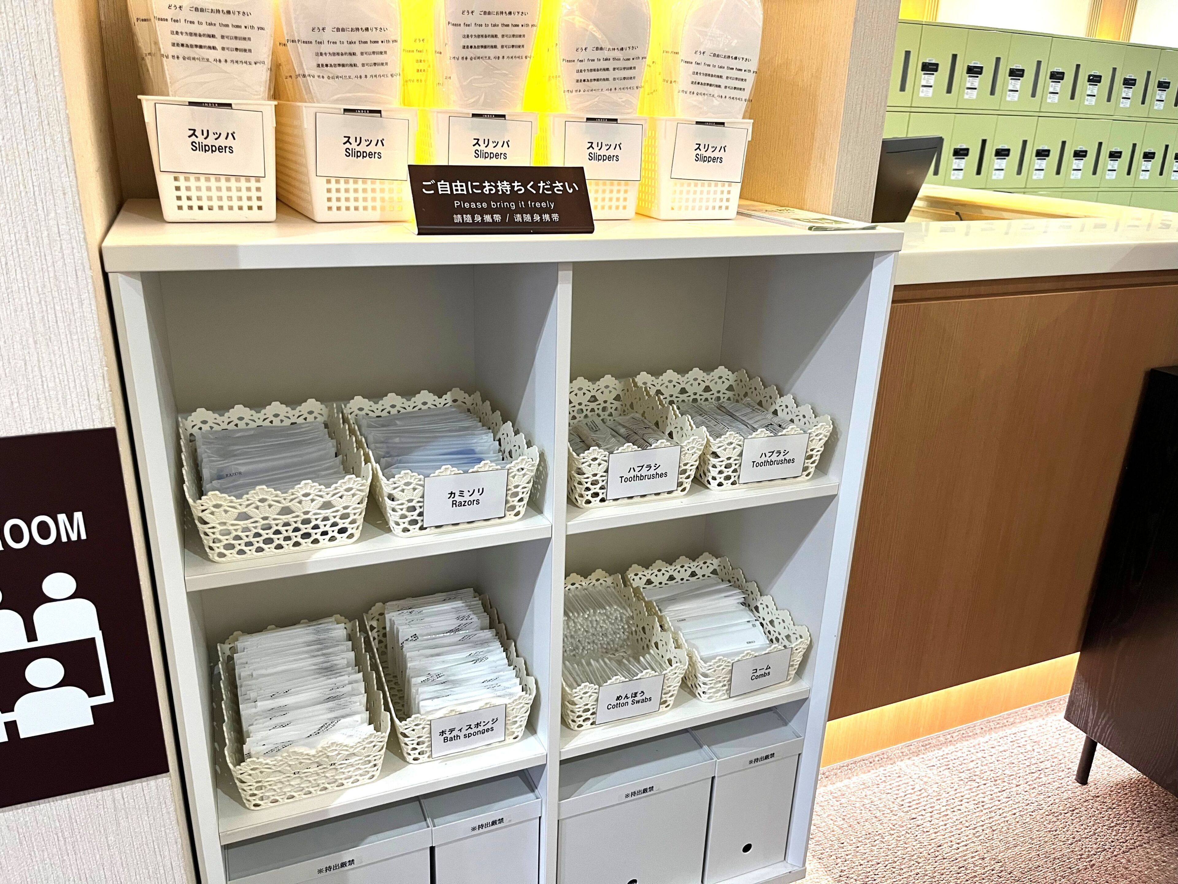 Un'area della reception di un hotel con uno scaffale che espone diversi articoli da toilette, come pantofole, spazzolini, rasoi e spugne da bagno.