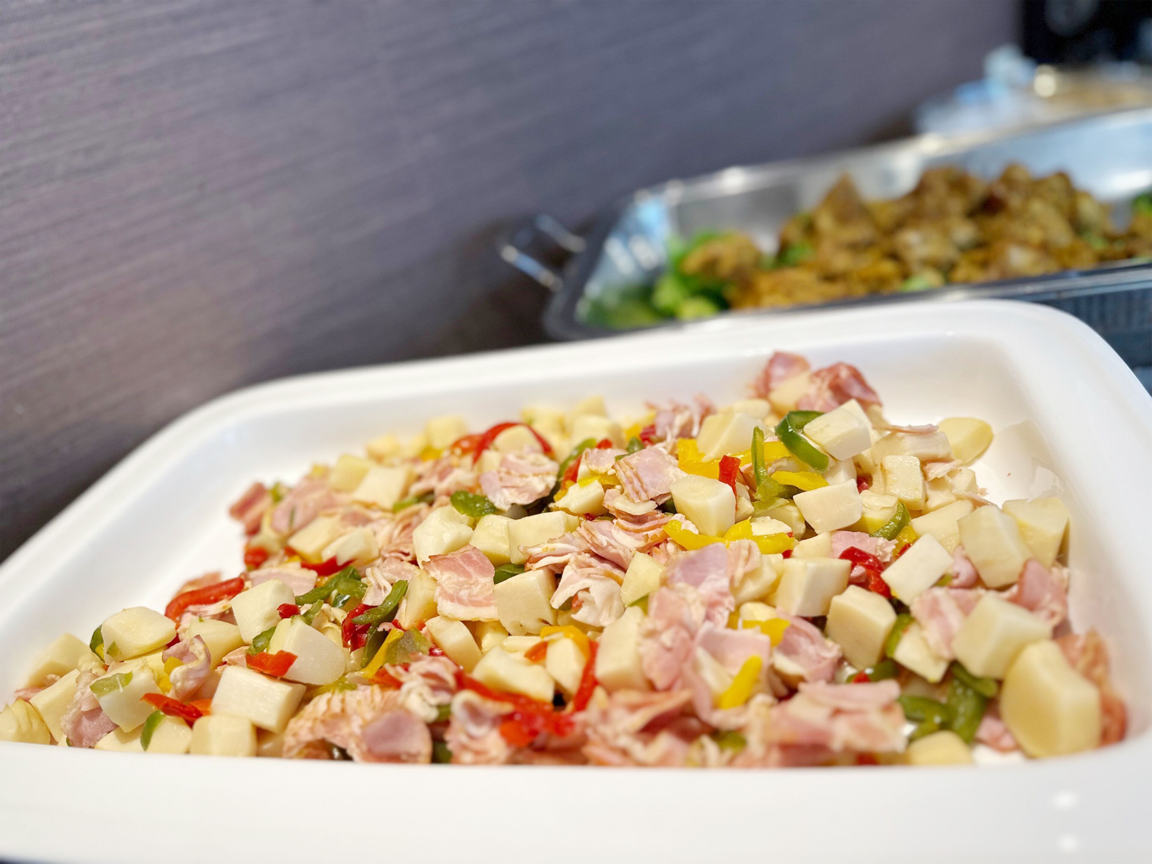 A white rectangular dish filled with diced ham, potatoes, and bell peppers.