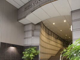 Interior de un hotel moderno con una escalera curva, un letrero que indica un nivel premium y una planta en maceta.