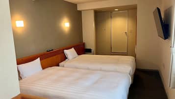 Une chambre d’hôtel avec deux lits, un téléviseur fixé au mur et une porte donnant sur la salle de bain.