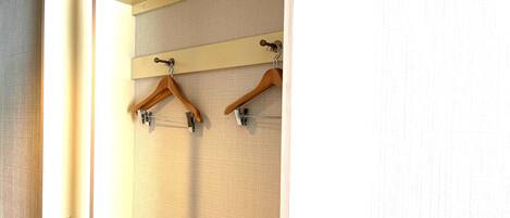 A room with a textured wall and a wooden coat rack with two hangers.