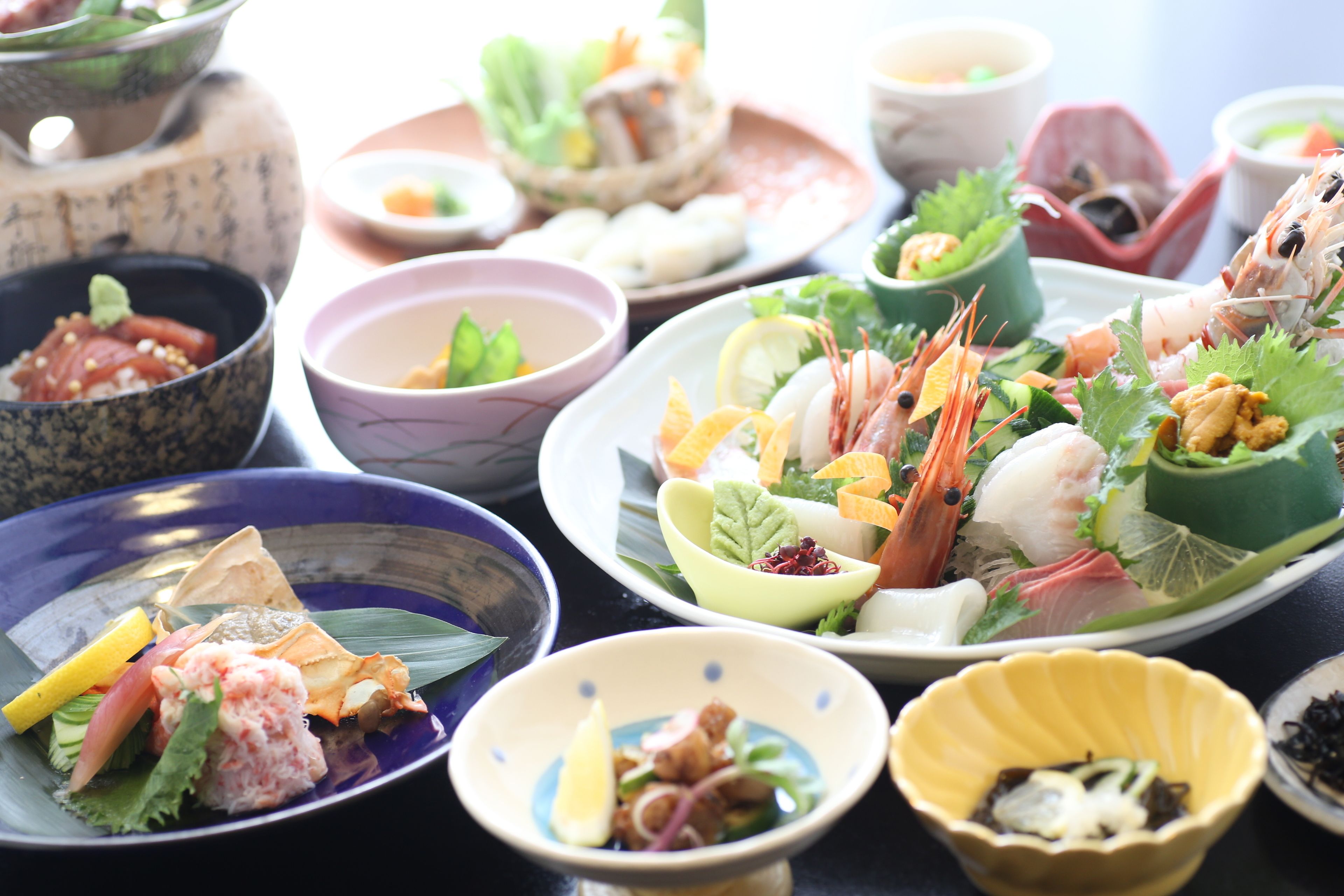 Diverse gerechten op een tafel, waaronder sushi, sashimi en andere zeevruchten.