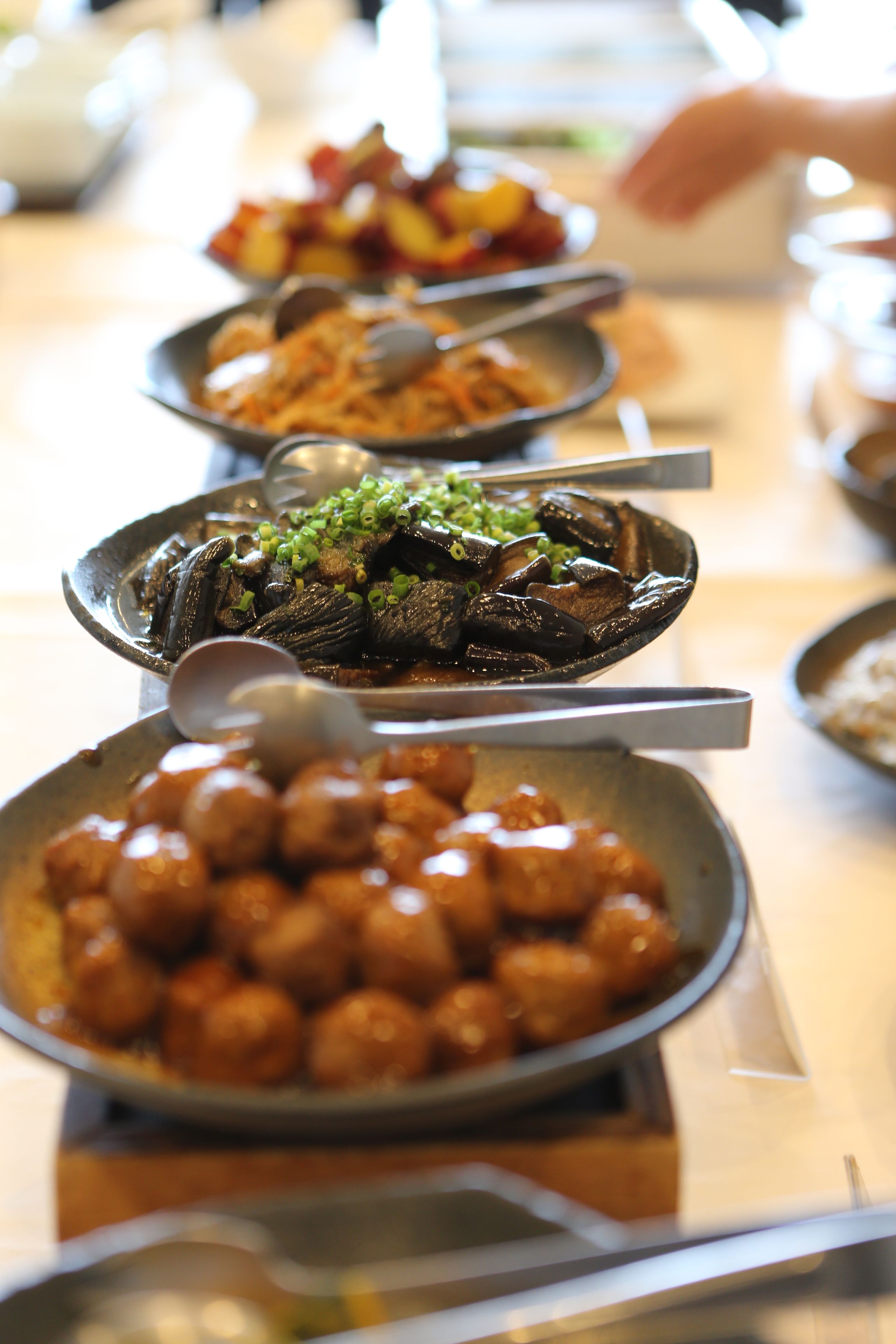 A buffet table with various dishes, including seafood and meat, arranged in metal serving dishes.