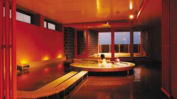 Um spa moderno com uma banheira de hidromassagem circular, bancos e vista para a cidade ao entardecer.