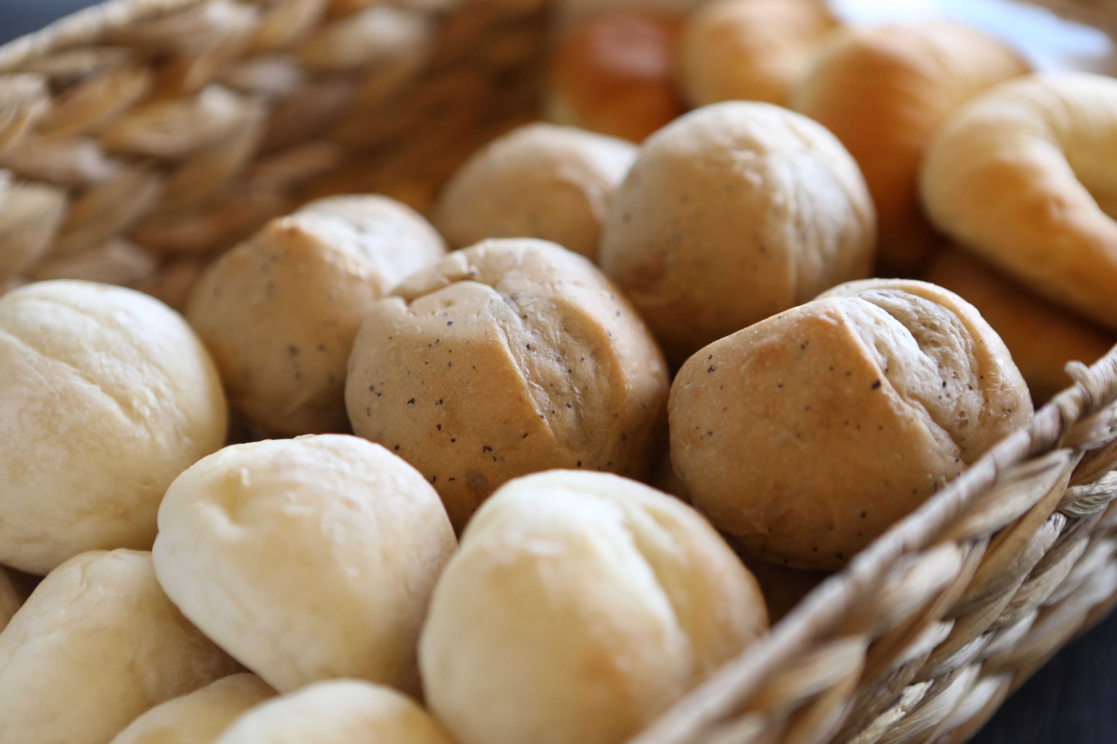 A basket of round, soft bread rolls with a visible speckled pattern.