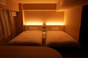 A hotel room with two single beds, a bedside table, and a headboard with integrated lighting. - Hotel Alpha Inn Akita (Akita)