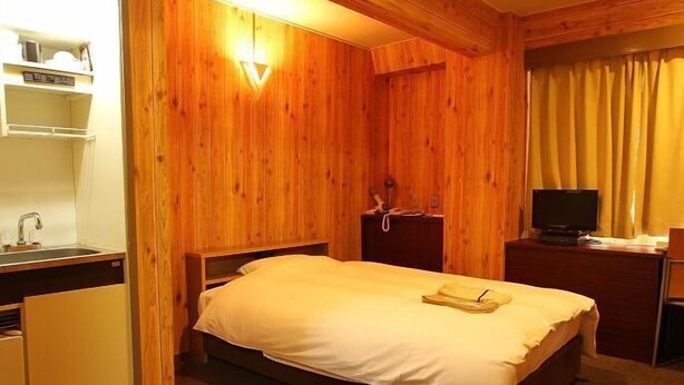 A room with a bed, a desk, a television, and a small kitchenette. - Benefit Hotel Okayama 1 (Okayama)