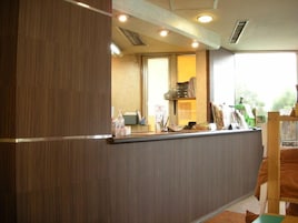 Un mostrador de recepción con un panel de madera, una ventana con vistas y un mostrador con varios objetos.