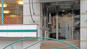 A hotel entrance with a sign reading 'Benefit Hotel,' a glass door, and a metal staircase leading up. - Benefit Hotel Okayama 1 (Okayama)