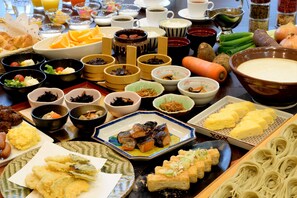Una mesa con diversos platos, incluyendo sushi, tempura y fideos.